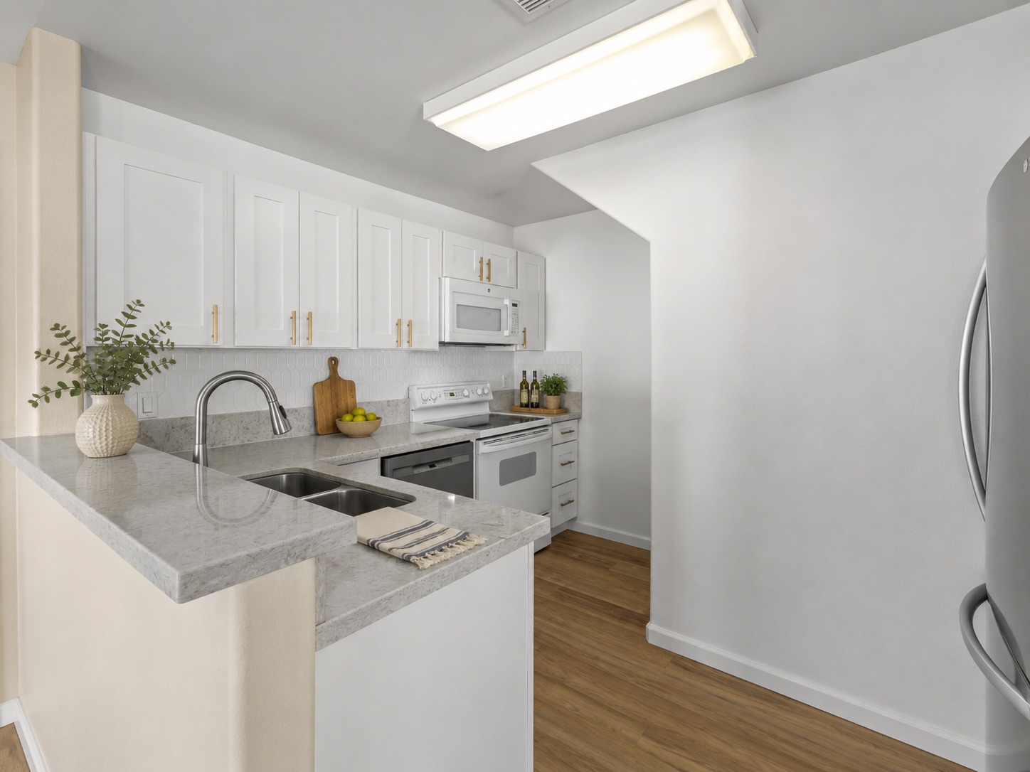 Kitchen with white cabinetry, quartz counters, and stainless refrigerator